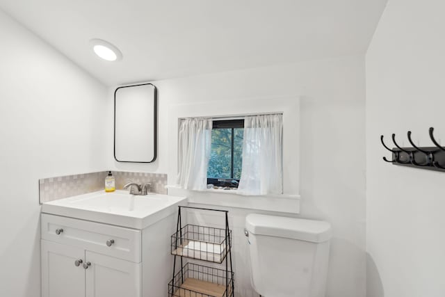 bathroom with vanity, toilet, and decorative backsplash