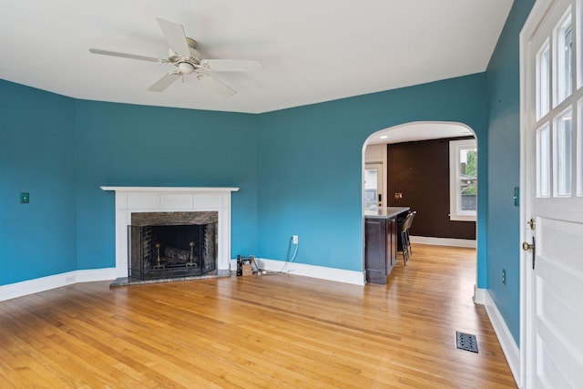 unfurnished living room featuring ceiling fan, a high end fireplace, and light hardwood / wood-style flooring