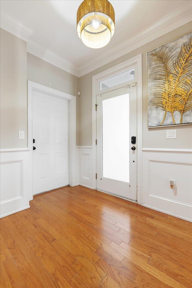 foyer entrance with crown molding and light hardwood / wood-style flooring