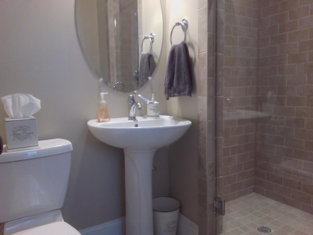 bathroom featuring a shower with door and toilet