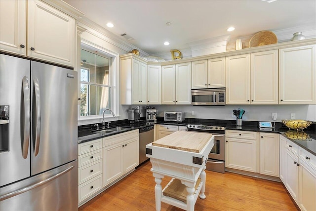 kitchen featuring cream cabinets, appliances with stainless steel finishes, sink, and light hardwood / wood-style flooring