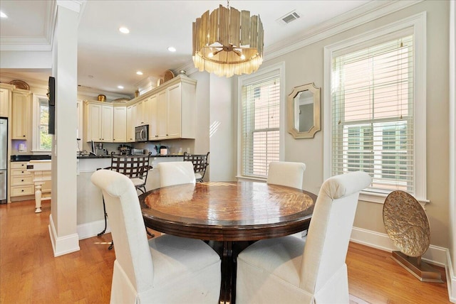 dining room with ornamental molding, a chandelier, and light hardwood / wood-style floors