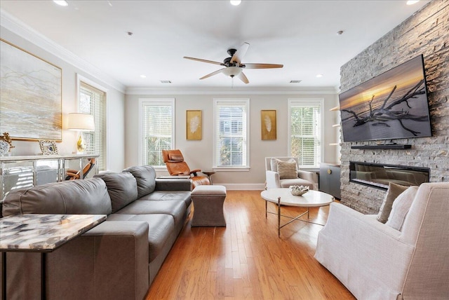 living room featuring crown molding, ceiling fan, a fireplace, and light hardwood / wood-style flooring