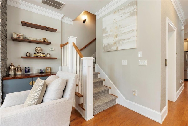 stairway with crown molding and hardwood / wood-style floors