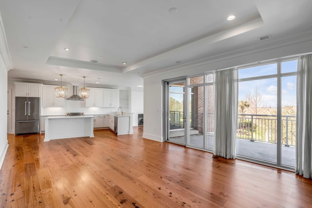 interior space with a sink, a tray ceiling, light wood-type flooring, and recessed lighting