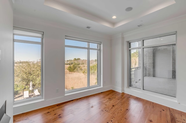 spare room with visible vents, a raised ceiling, hardwood / wood-style floors, recessed lighting, and baseboards