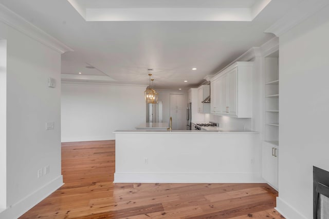 kitchen with light wood-type flooring, white cabinetry, a peninsula, a fireplace, and a raised ceiling