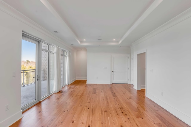 spare room with a raised ceiling, ornamental molding, recessed lighting, light wood-style floors, and baseboards