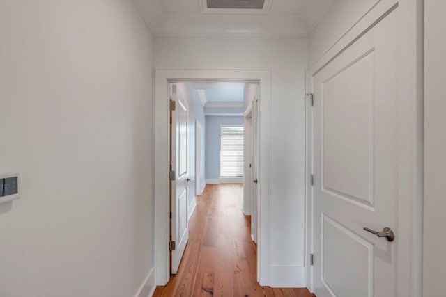 hallway featuring visible vents, crown molding, and light wood-style floors