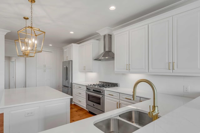 kitchen featuring high quality appliances, light countertops, white cabinets, wall chimney exhaust hood, and a sink