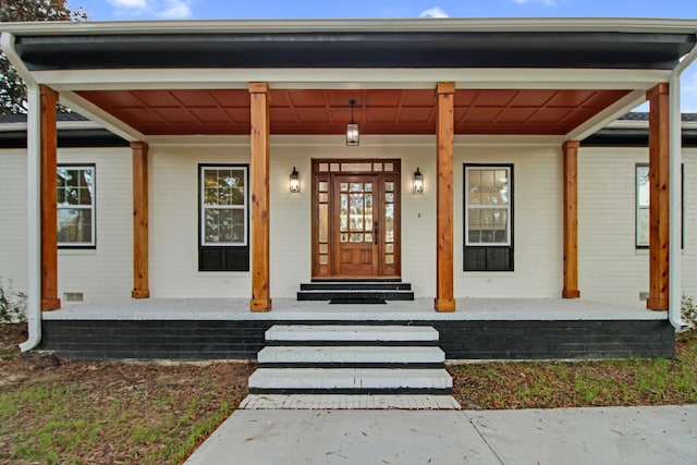 doorway to property with covered porch and brick siding