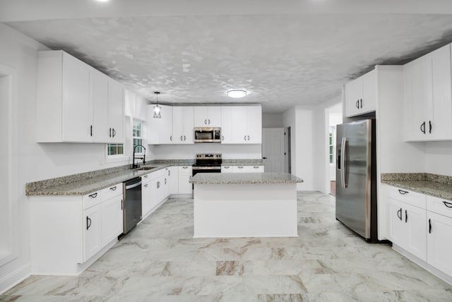 kitchen with stainless steel appliances, a center island, white cabinetry, and a sink