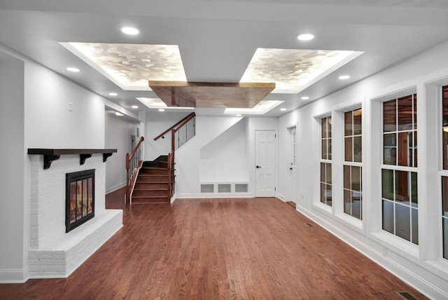 basement featuring baseboards, wood finished floors, stairs, a brick fireplace, and recessed lighting