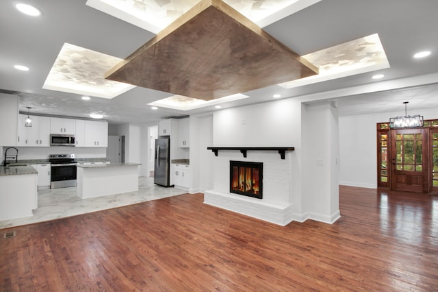 kitchen featuring appliances with stainless steel finishes, open floor plan, a sink, and light wood finished floors