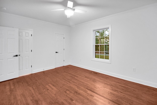 unfurnished room featuring baseboards, wood finished floors, and crown molding