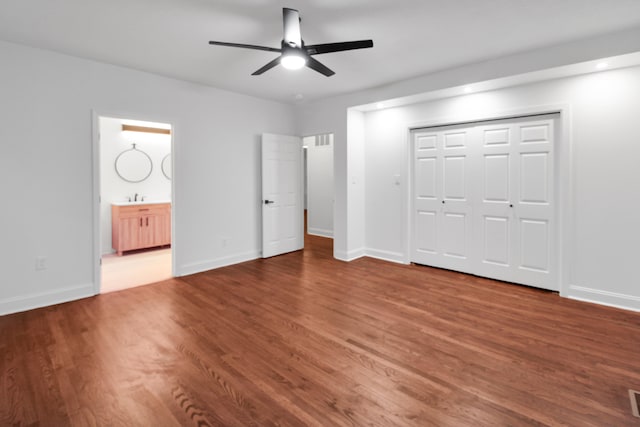 unfurnished bedroom featuring visible vents, baseboards, connected bathroom, wood finished floors, and a sink