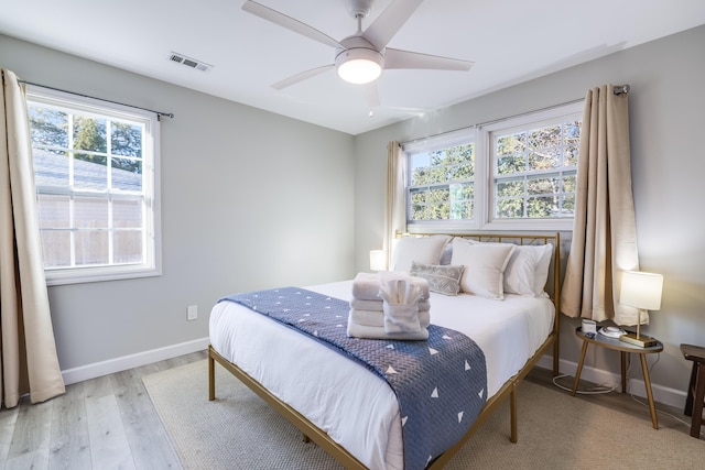 bedroom featuring baseboards, multiple windows, visible vents, and light wood-style floors