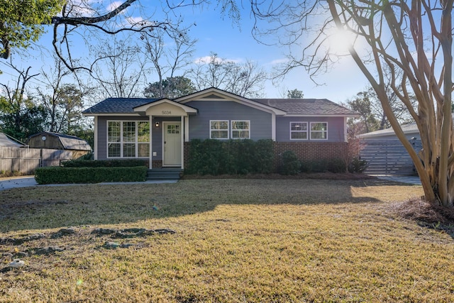 view of front of house with brick siding, a front lawn, and fence