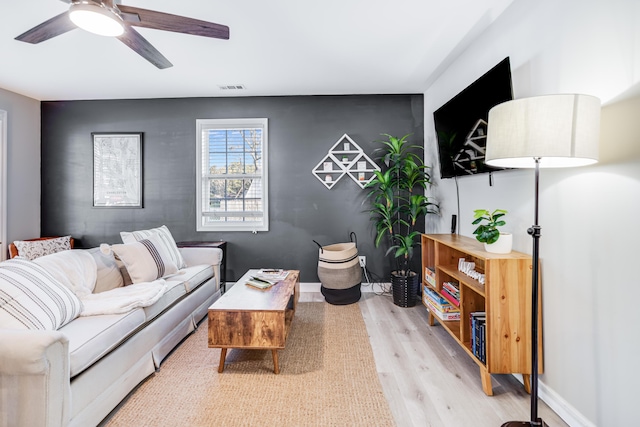 living room with a ceiling fan, light wood-style flooring, visible vents, and baseboards