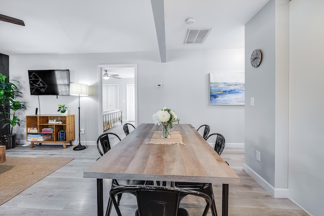 dining room featuring a ceiling fan, light wood-style flooring, visible vents, and baseboards