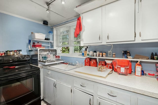 kitchen with light countertops, black range with electric stovetop, white cabinetry, a sink, and track lighting