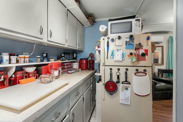 kitchen with white appliances, light wood-style floors, light countertops, gray cabinets, and a wall mounted air conditioner