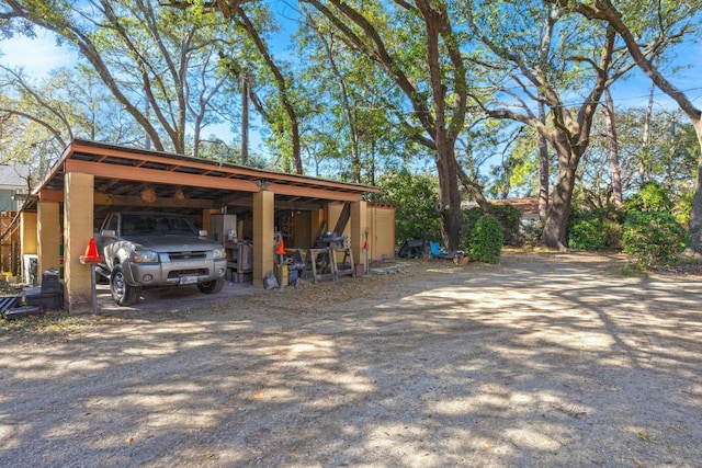 exterior space with dirt driveway, a carport, and an outbuilding