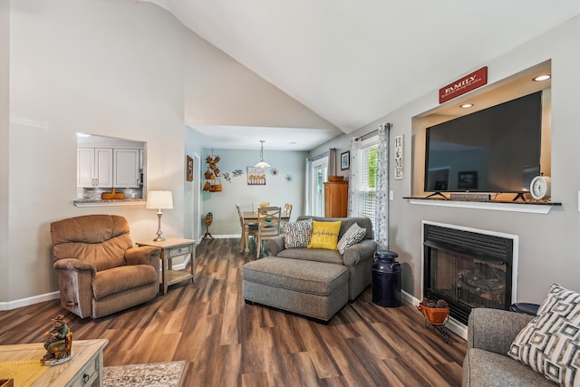 living area with baseboards, wood finished floors, high vaulted ceiling, and a fireplace