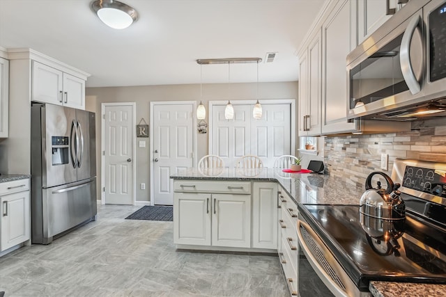 kitchen featuring backsplash, hanging light fixtures, a peninsula, stone counters, and stainless steel appliances