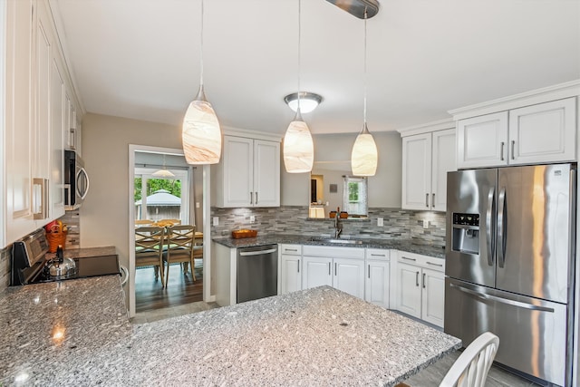 kitchen with decorative backsplash, dark stone counters, a peninsula, and stainless steel appliances
