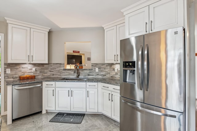 kitchen featuring decorative backsplash, a sink, white cabinets, dark stone counters, and stainless steel appliances
