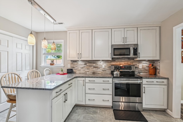 kitchen featuring appliances with stainless steel finishes, a peninsula, decorative backsplash, a kitchen bar, and pendant lighting