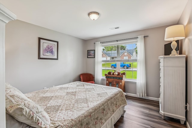 bedroom featuring visible vents, baseboards, and wood finished floors