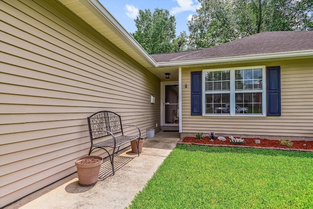 entrance to property with a lawn and a shingled roof