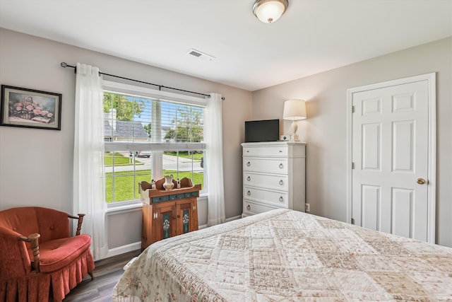 bedroom with baseboards, visible vents, and wood finished floors