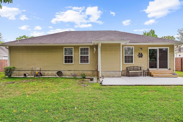rear view of property featuring a lawn, entry steps, fence, and a patio