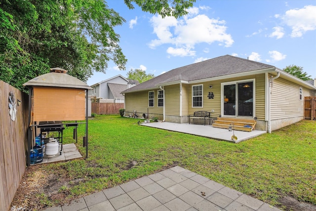 back of house featuring entry steps, a patio, a yard, and a fenced backyard