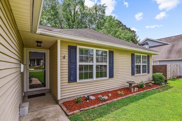 exterior space with a yard, fence, and roof with shingles
