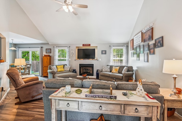 living room featuring a ceiling fan, vaulted ceiling, dark wood-type flooring, and a wealth of natural light