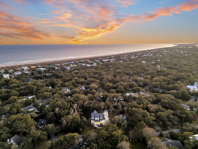 aerial view at dusk featuring a water view and a view of the beach