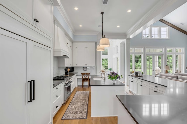 kitchen featuring backsplash, high quality appliances, white cabinets, and hanging light fixtures