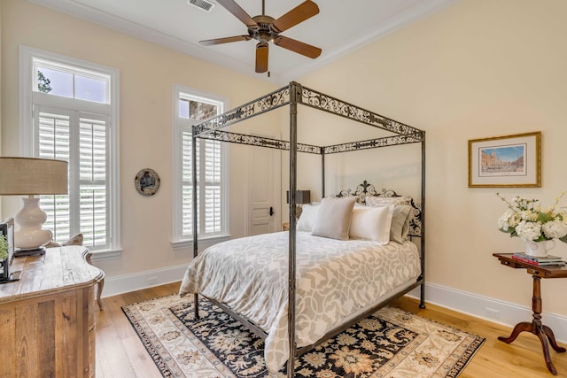 bedroom with ceiling fan, multiple windows, hardwood / wood-style flooring, and crown molding