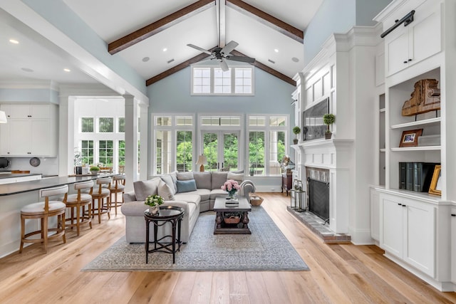 living room featuring light wood-type flooring, a fireplace, and beamed ceiling