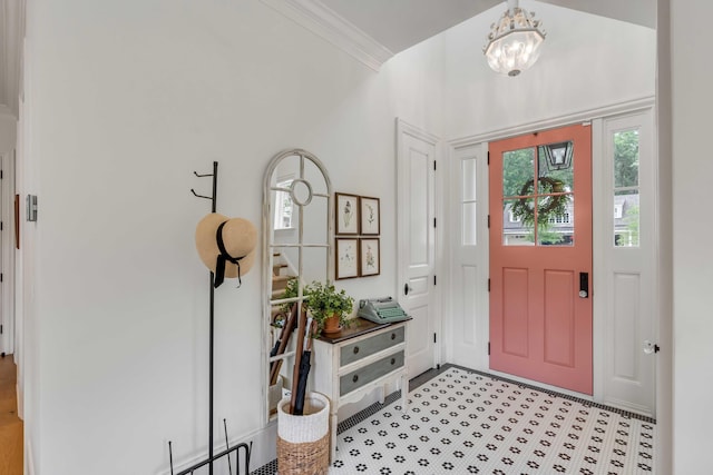 foyer with ornamental molding and an inviting chandelier