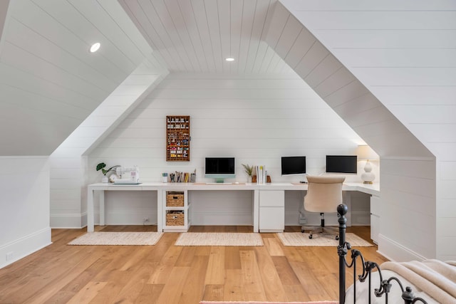 home office with built in desk, light hardwood / wood-style flooring, and wooden walls