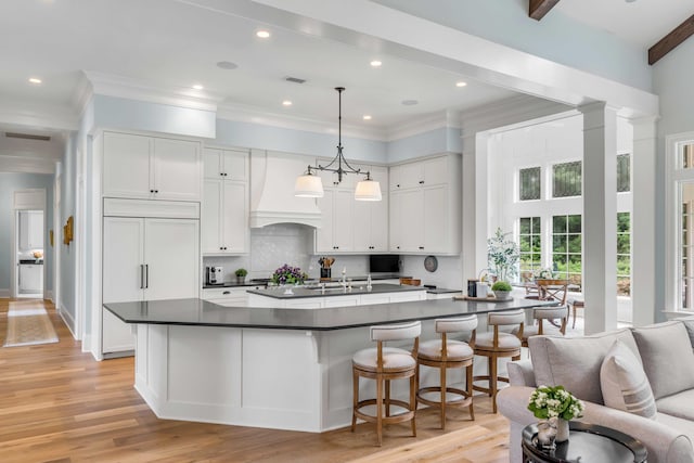 kitchen featuring pendant lighting, paneled refrigerator, white cabinetry, and beam ceiling