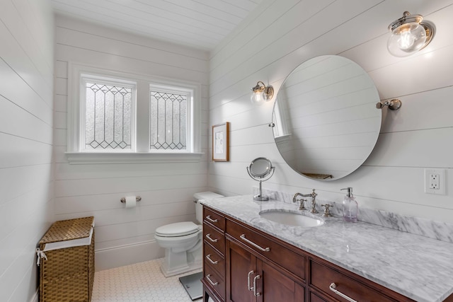 bathroom featuring toilet, vanity, tile patterned flooring, and wooden walls