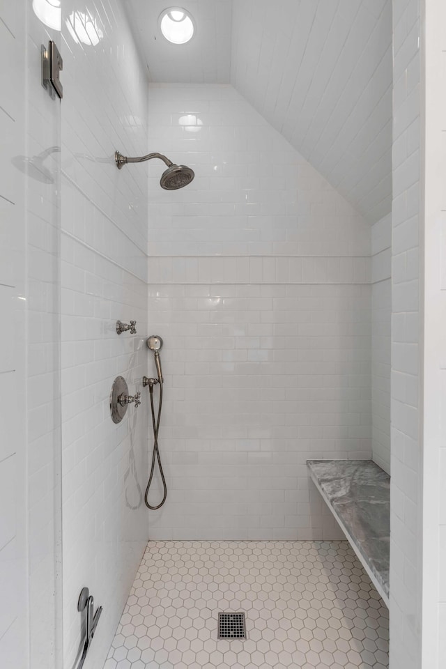 bathroom featuring vaulted ceiling and a tile shower