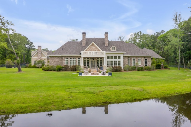 rear view of house featuring a water view, an outdoor living space, a patio area, and a yard