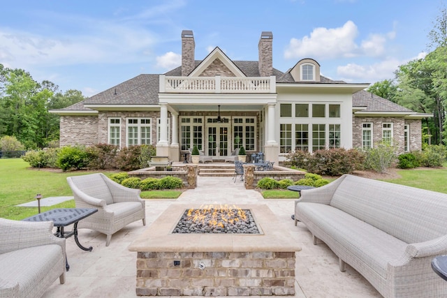 rear view of house featuring ceiling fan, a patio area, an outdoor living space with a fire pit, a balcony, and french doors